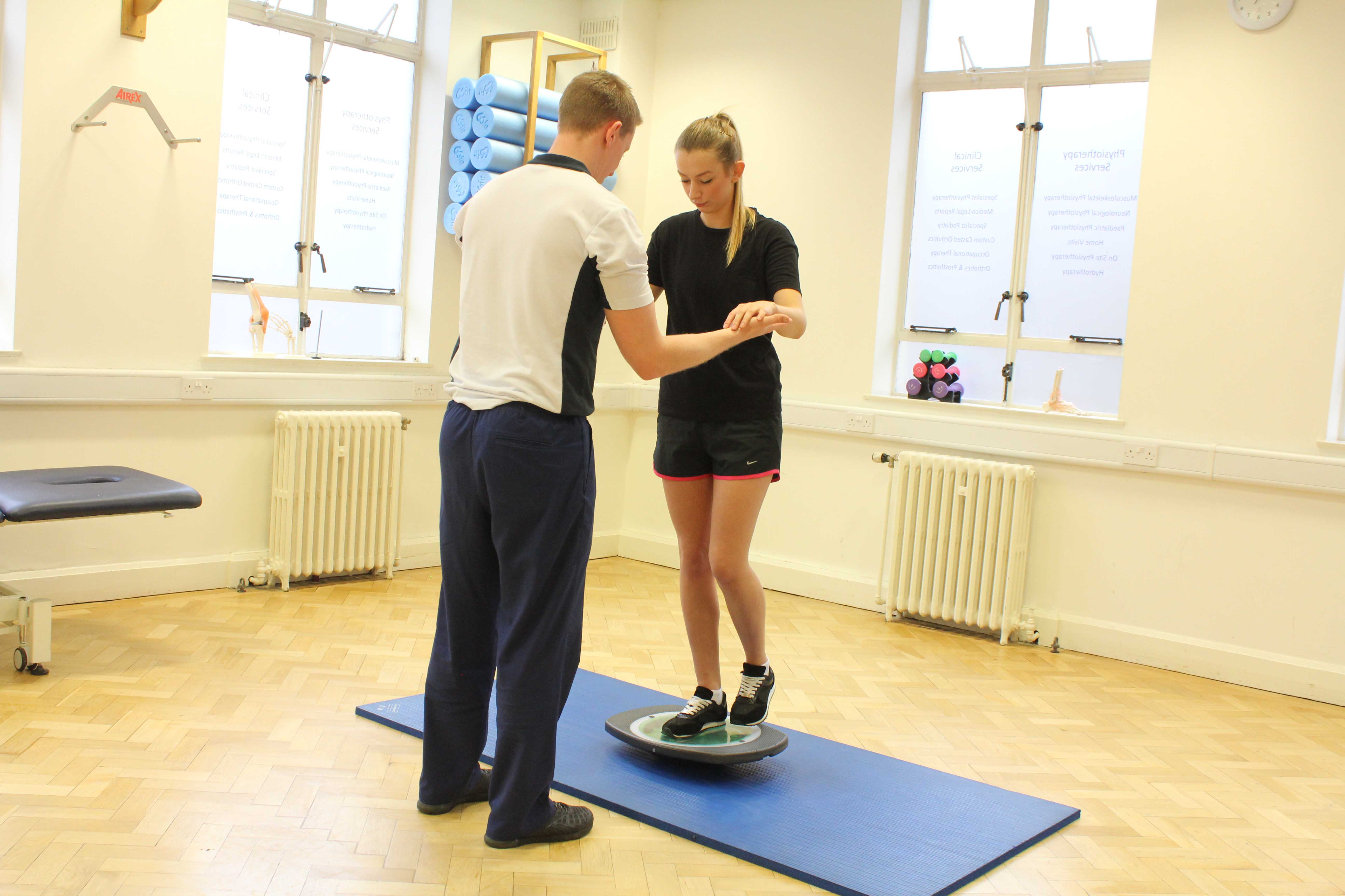 Physiotherapist using a wobble board to retrain a clients core stability