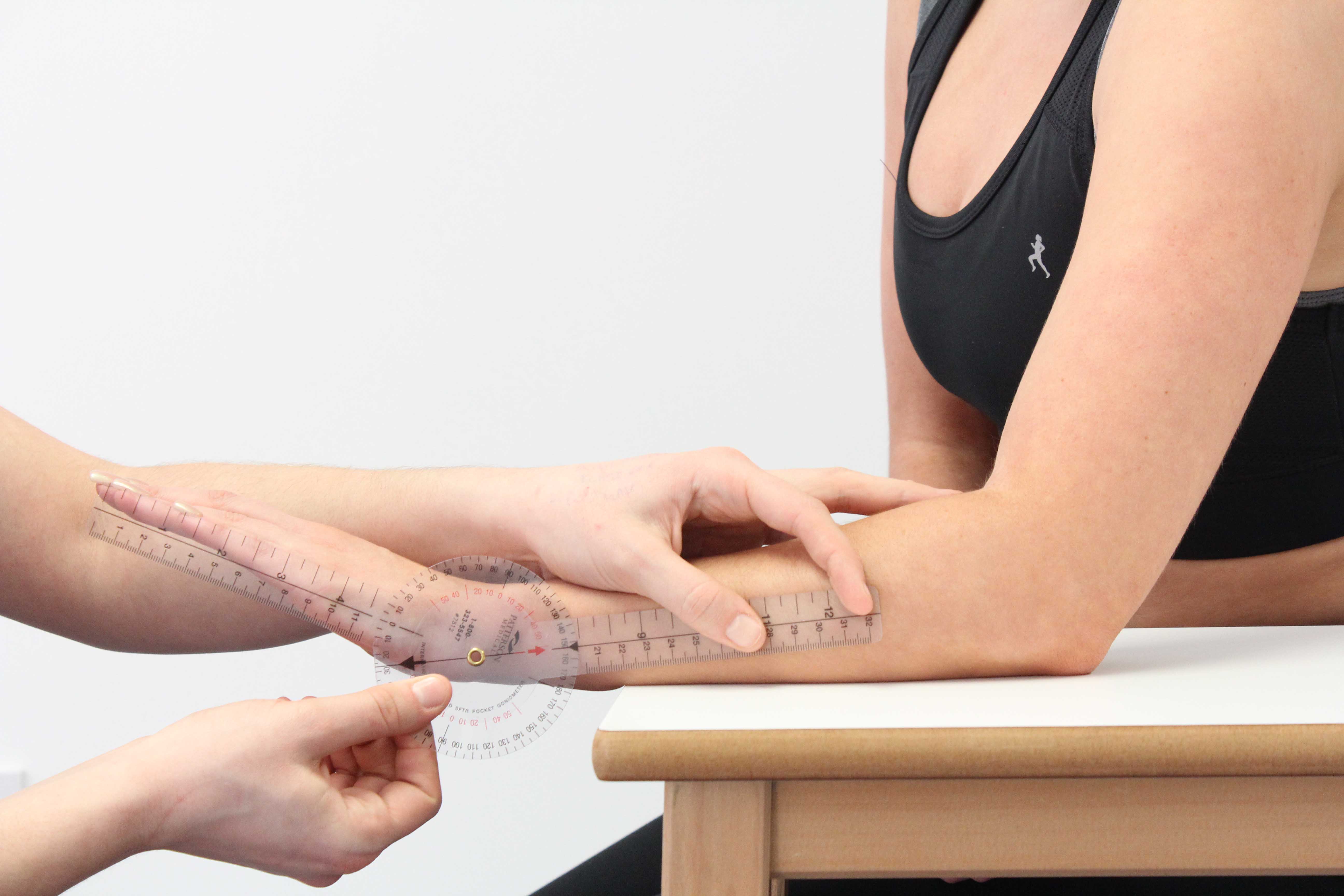 Therapist measuring wrist extension using a goniometer
