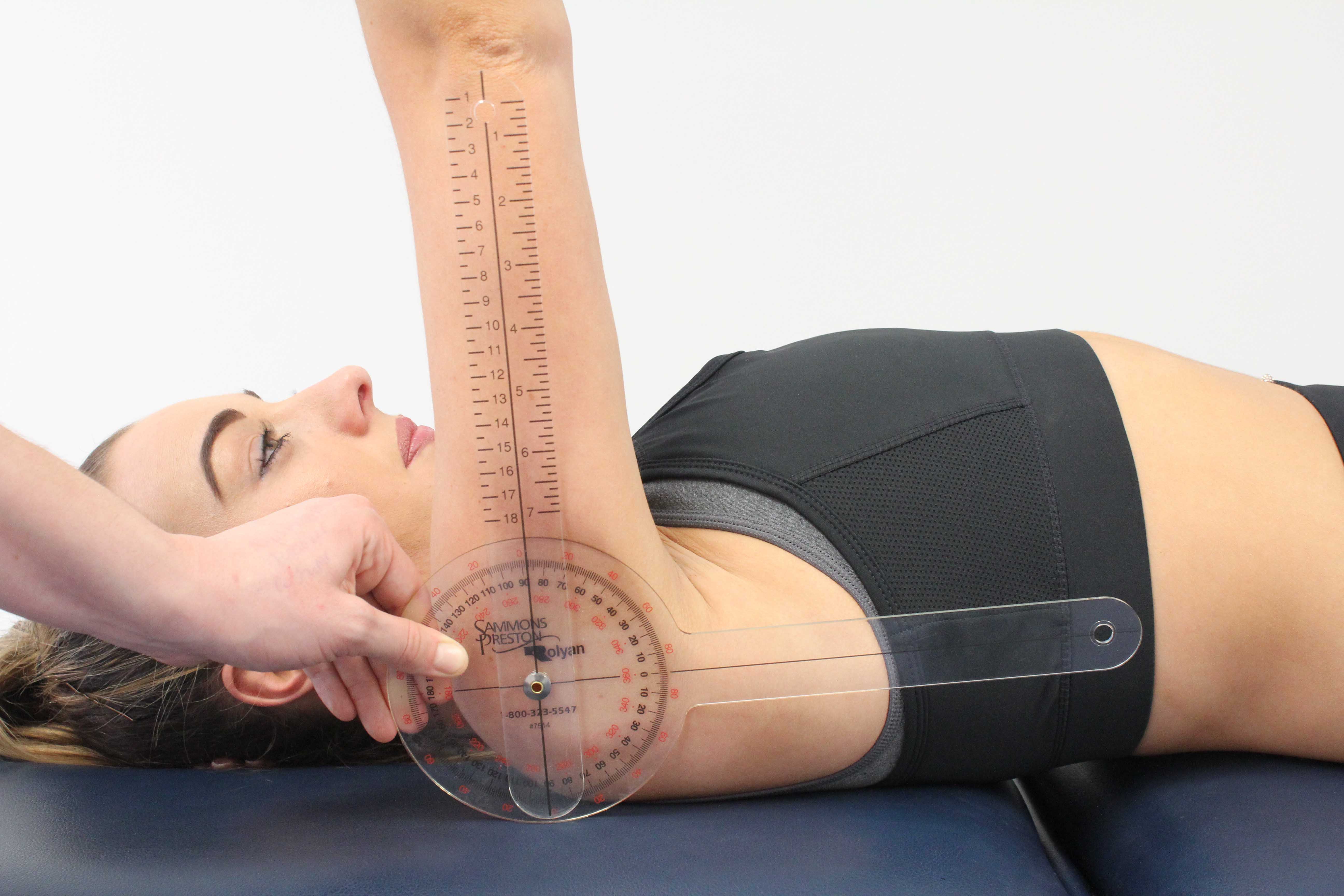 Physiotherapist measuring available range of movement at the shoulder using a goniometer