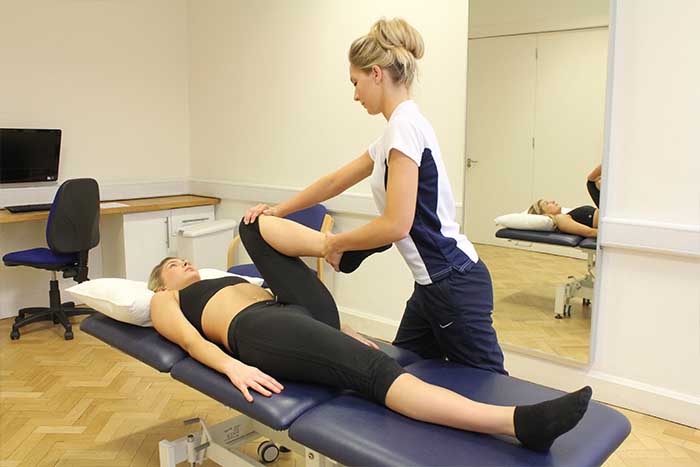 Customer receiving a leg stretch while in a relaxed position in Manchester Physio Clinic