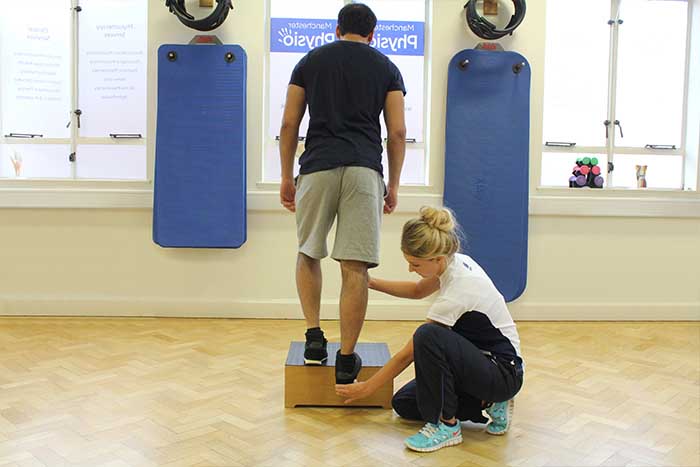 Customer receiving leg excersises with aid from instructor in Manchester Physio Clinic