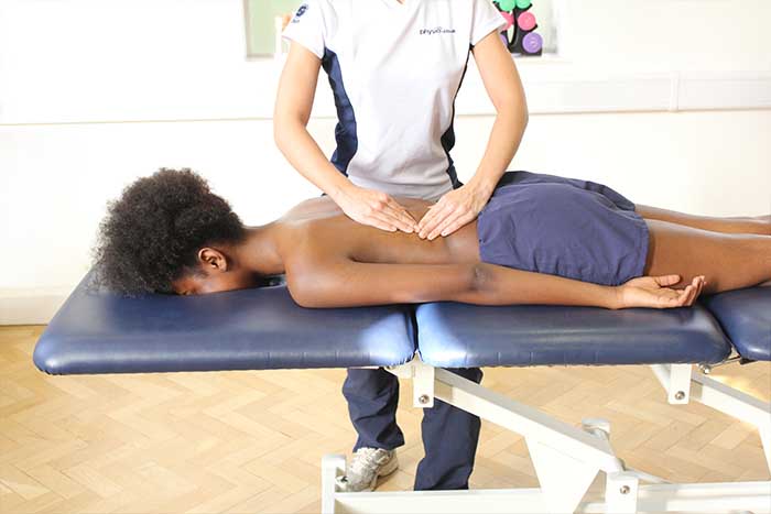 Customer reciving a lower back massage while in a relaxed position in Manchester Physio Clinic