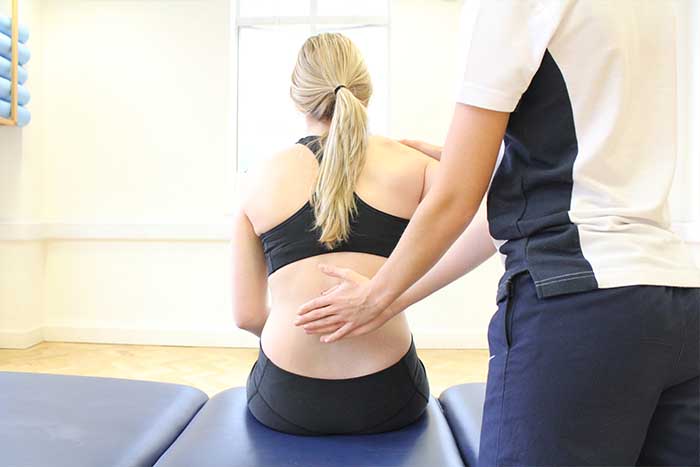 Customer receiving back support while in a sitting position in Manchester Physio Clinic