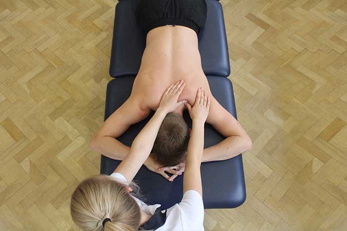 Customer receiving a shoulder massage while in a relaxed position in Manchester Physio Clinic