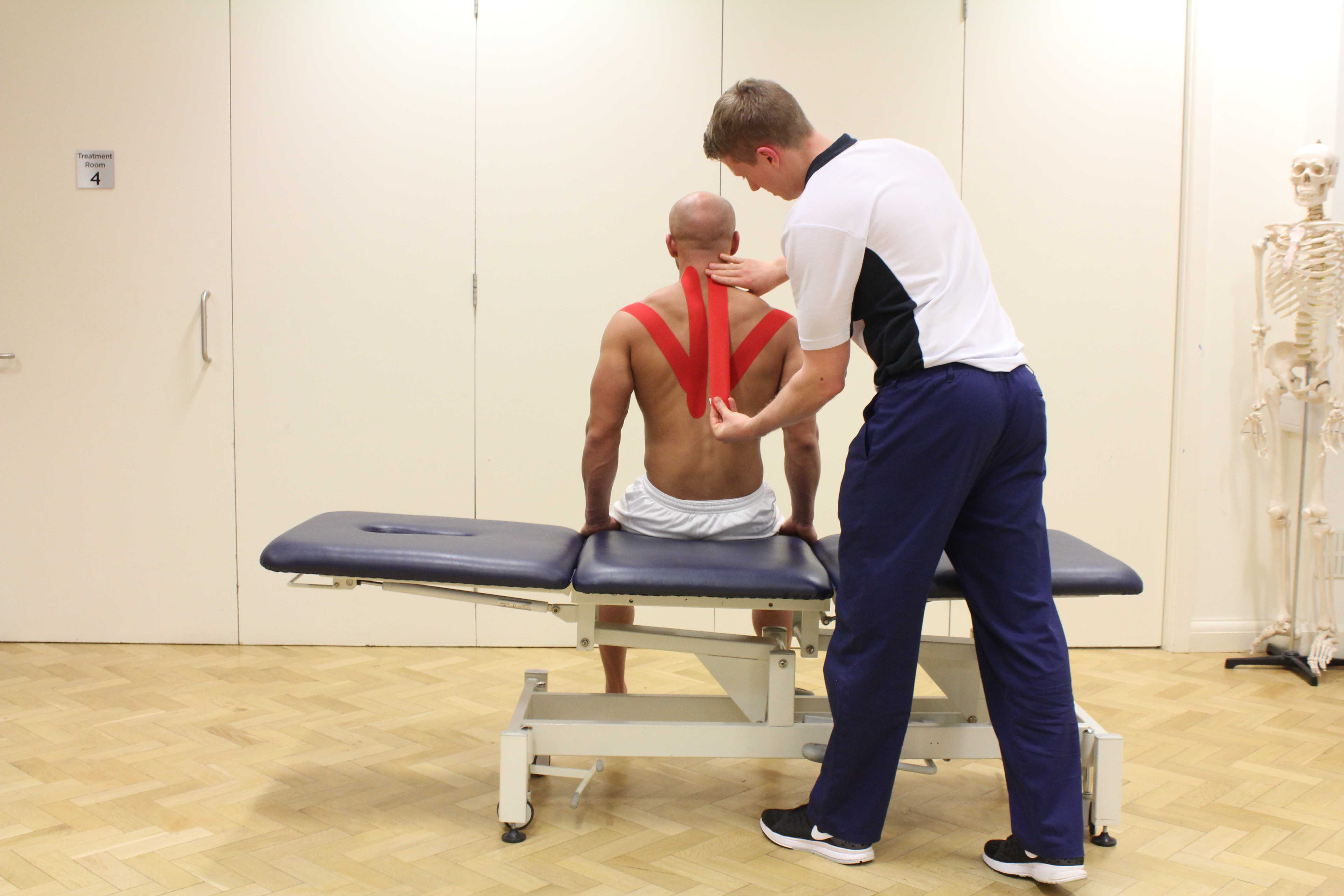 Experienced Physiotherapist using specialist tape to support and stabilise movement across the shoulders