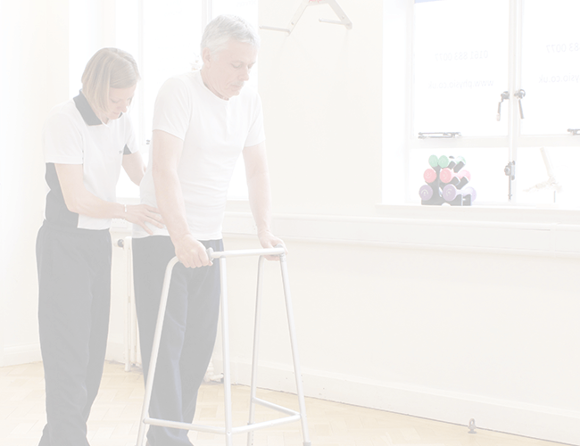 Elderly male patient recieves walking aid via trained physiotherapist and walking frame.