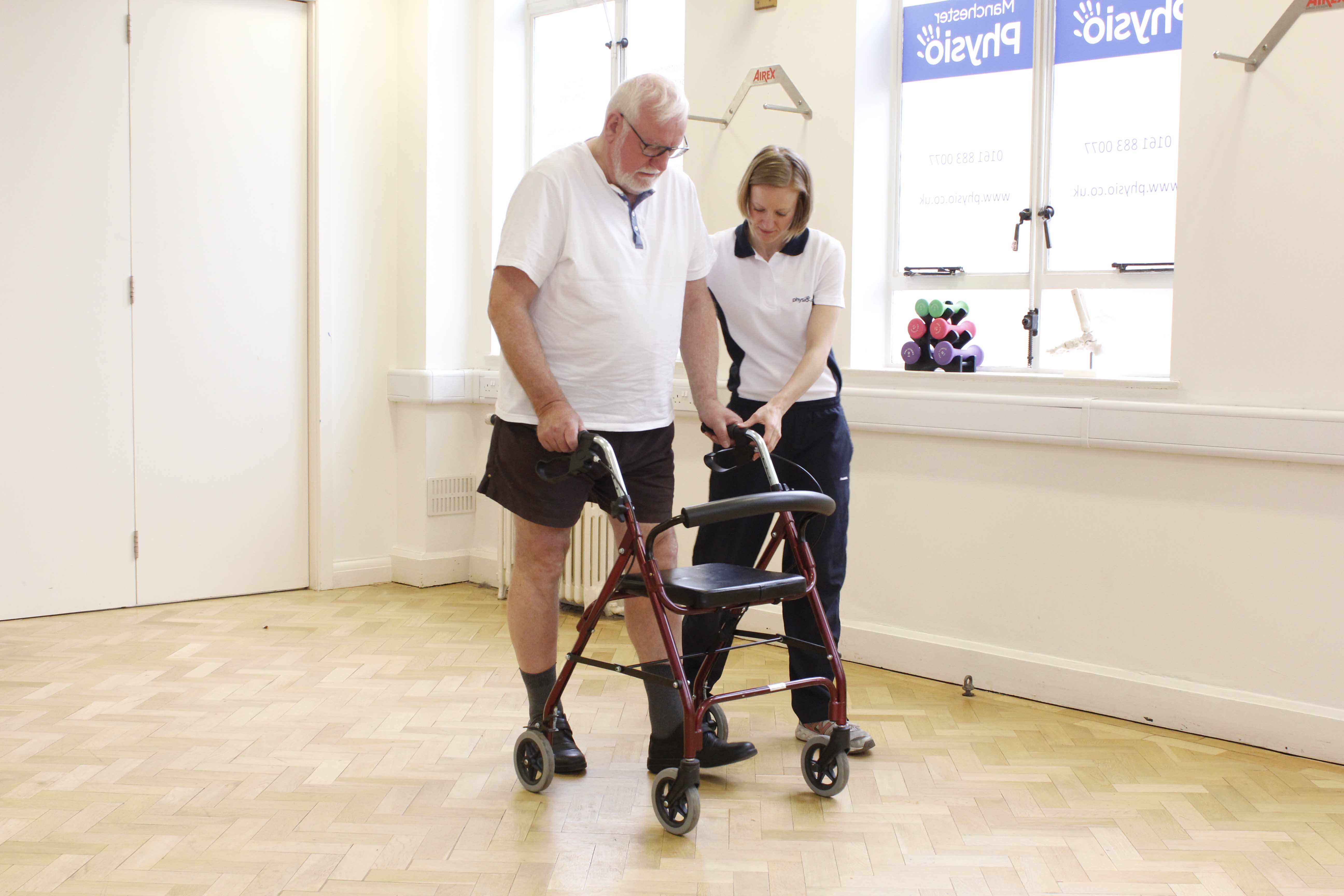 Specialist physiotherapist closely supervising mobility exercises using a rollator frame
