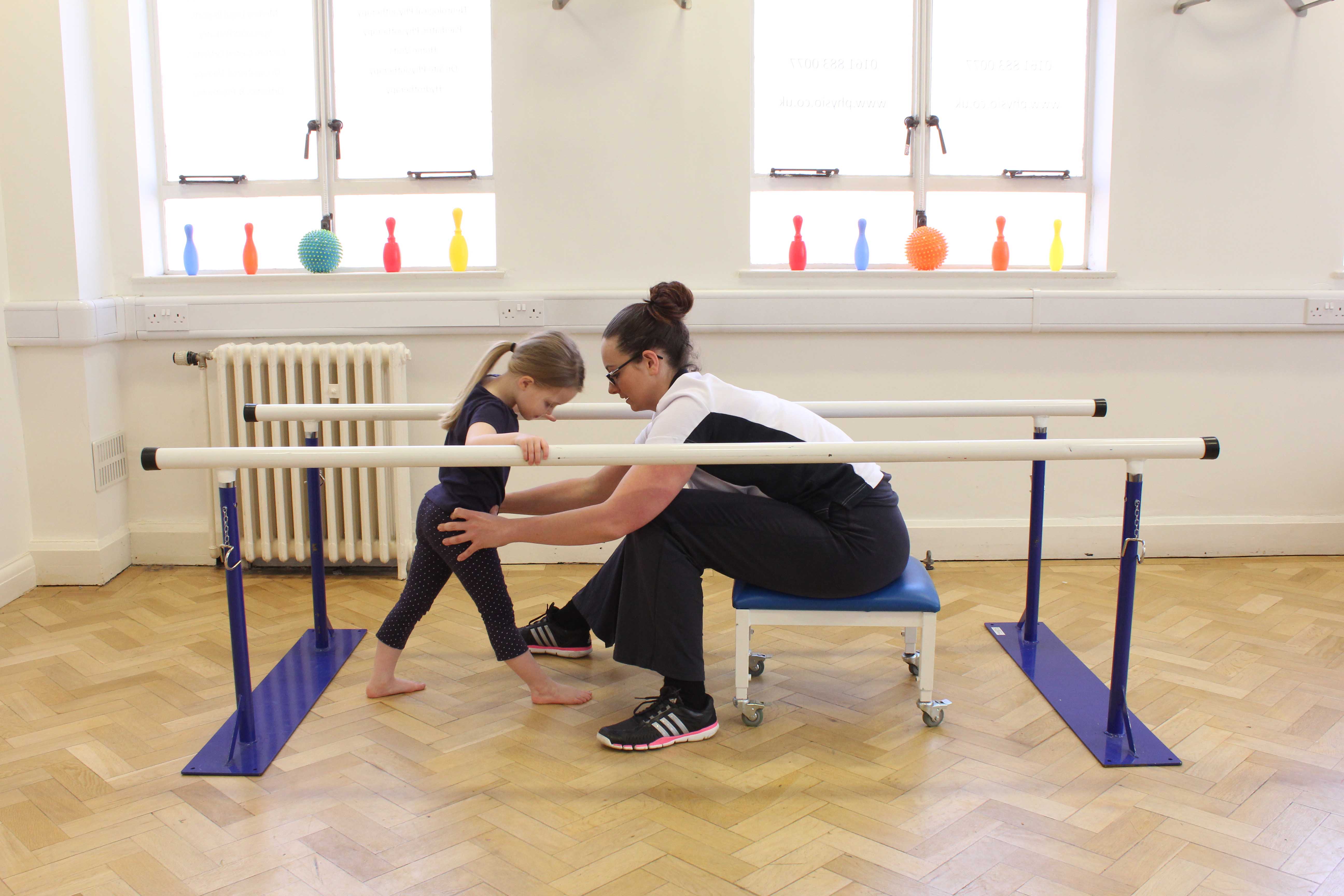 Mobility exercises assisted by the physiotherapist between the parallel bars