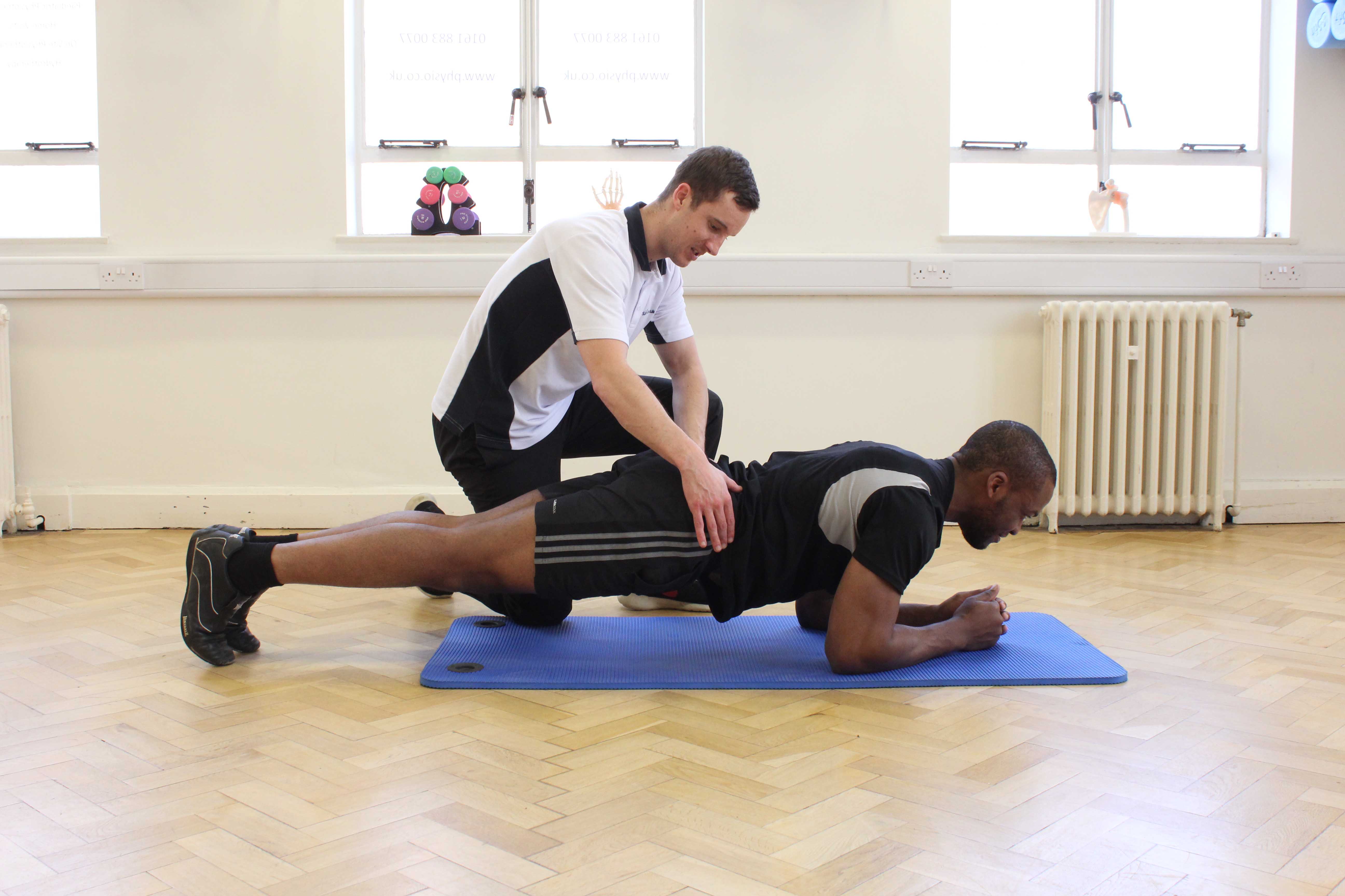 Planking toning exercises for the back supervised by an experienced physiotherapist