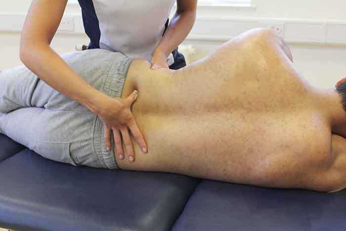 Customer receiving lower back massage while in a relaxed position in Manchester Physio Clinic