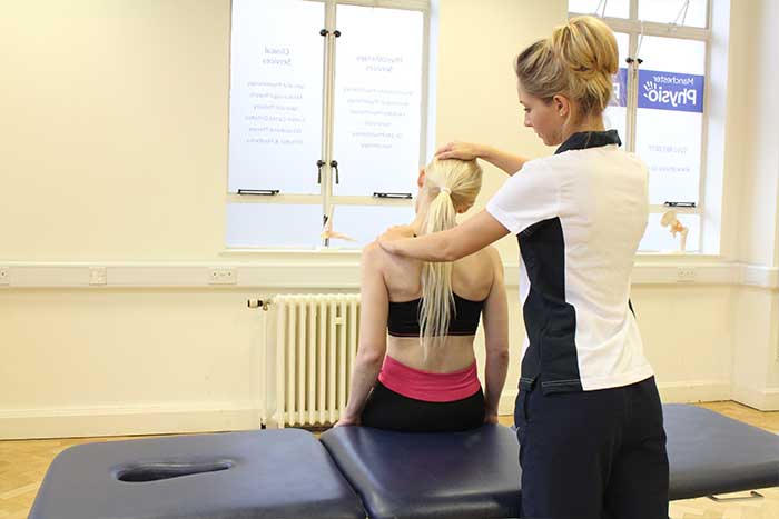 Customer receiving shoulder check in sitting up position in Manchester Physio Clinic
