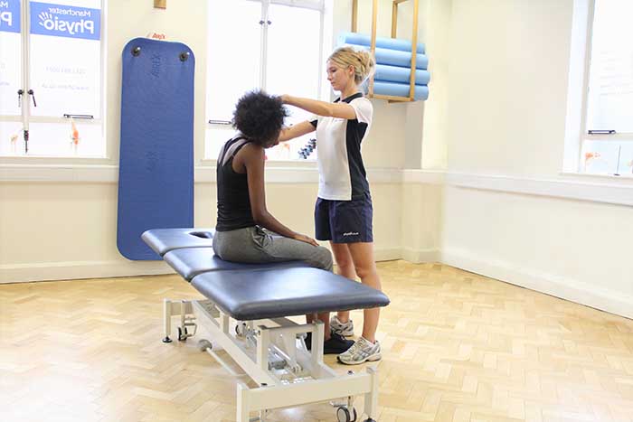 Customer receiving neck stretches aid from massager in Manchester Physio Clinic