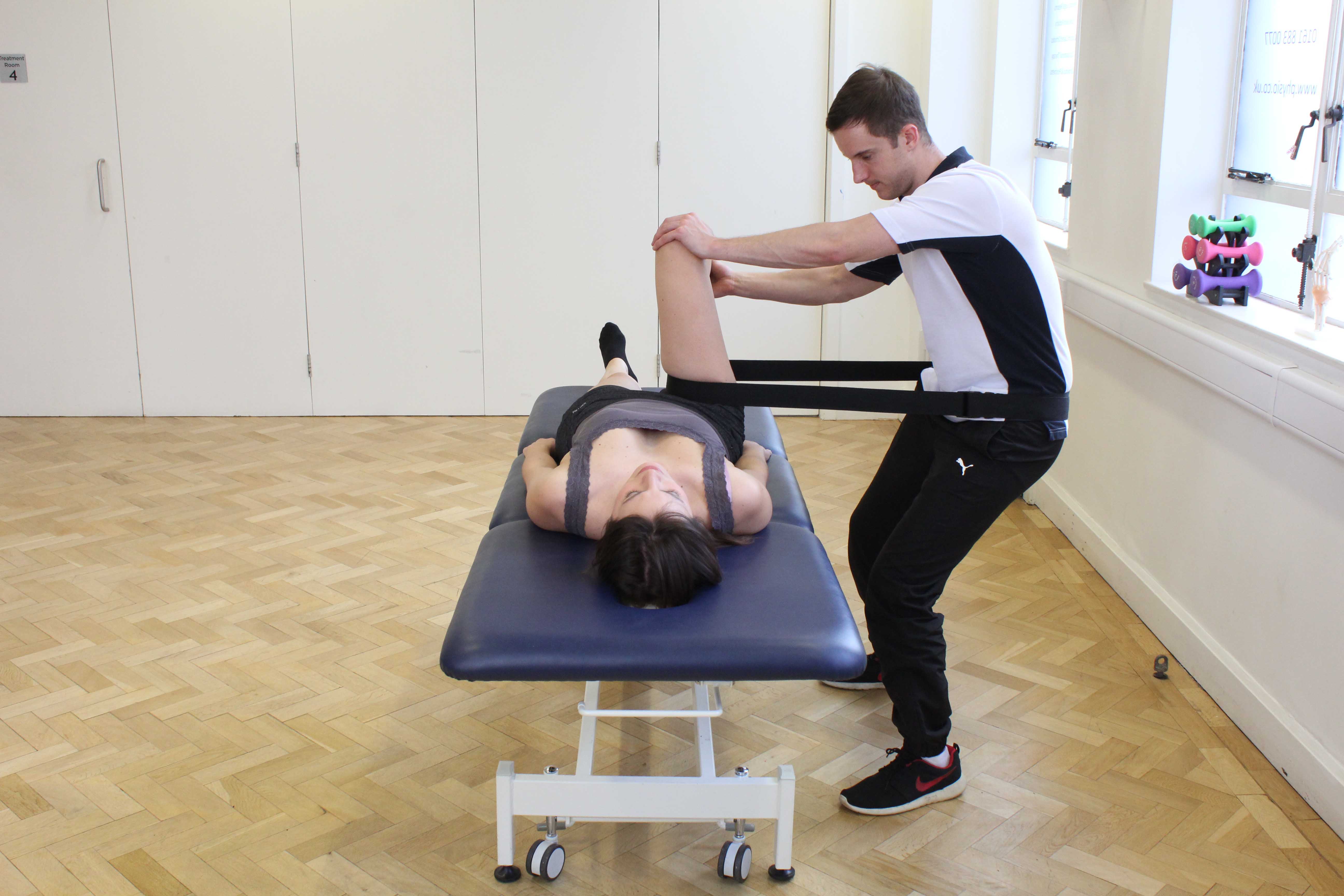 Physiotherapist using a strap to mobilise the hip joint